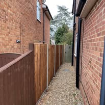 Wooden fence panels fitted in a narrow passage between brick houses