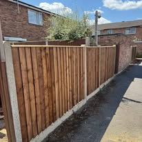Wooden fence panels with concrete posts installed along a brick house boundary