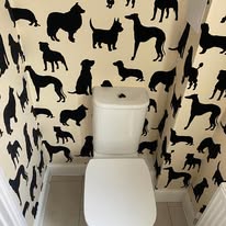 Black dog silhouette wallpaper hung in a small bathroom