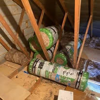 Insulation rolls laid on a boarded loft floor beside timber joists