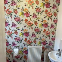 Bright floral wallpaper hung in a bathroom beside a sink
