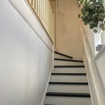 Finished hallway and staircase wall panelling beside black stair treads