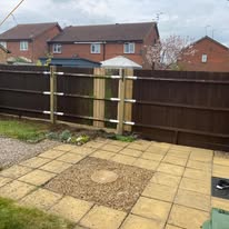 Dark brown wooden fence and garden gate leading to a rear garden