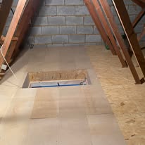 Loft floor boarding with a rectangular access hatch between timber joists