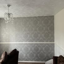 Grey patterned wallpaper hung in a living room with a central ceiling rose