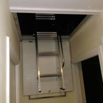 Silver aluminium loft ladder installed in a narrow hallway
