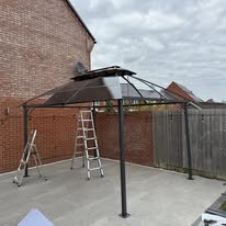 Gazebo frame part-assembled on a patio during an outdoor furniture build