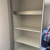 Clean white wardrobe shelves installed inside an empty cupboard space