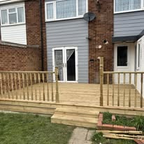 Completed timber decking with railings and steps outside a brick house