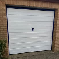 Freshly painted white sectional garage door on a brick house