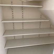 Adjustable white shelving fitted inside a wardrobe with metal bracket supports